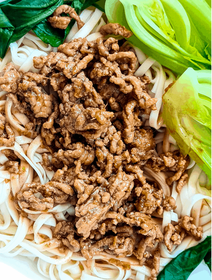 Close up of pork mince sauce on top of a bed of noodles