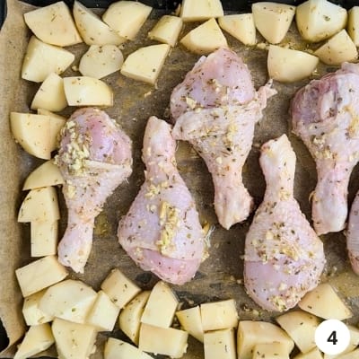 tray of chicken drumsticks and potatoes ready to be roasted in the oven