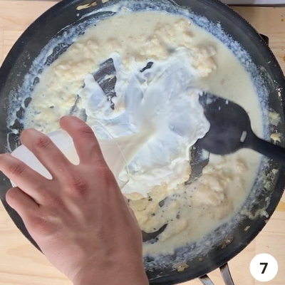 milk slowly being added into skillet of butter and flour mixture