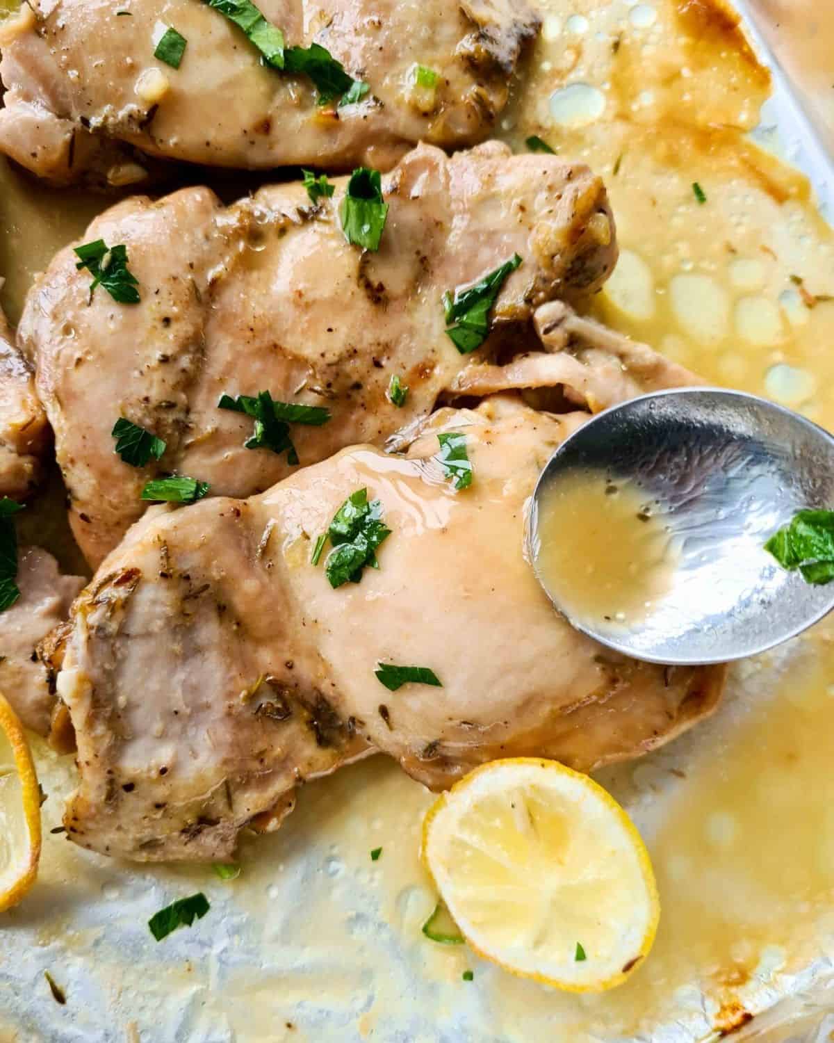Close up of basting lemon chicken thighs with its delicious juices