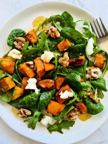 Fresh pumpkin salad on a white plate with a fork