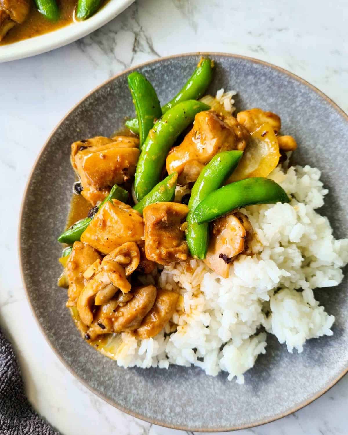 Chicken and snow peas stir fry served with rice on a plate