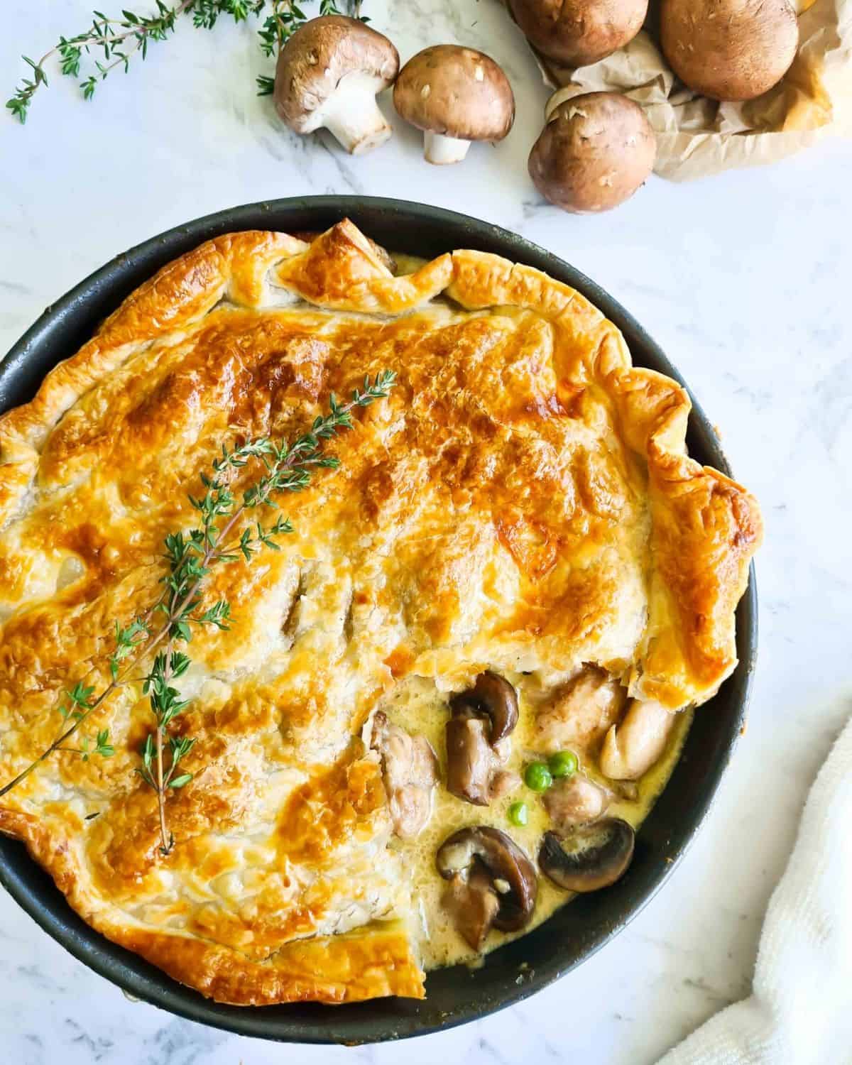 Chicken and mushroom pot pie with a portion of the pastry lifted showing creamy filling.