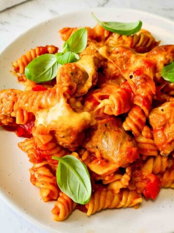 A plate of sausage pasta bake sprinkled with fresh basil