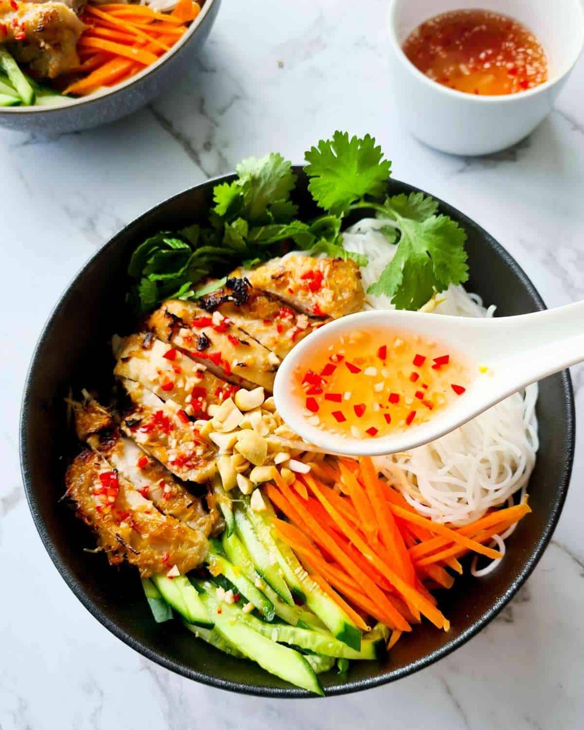 A spoonful of nuoc mum over a bowl of vermicelli bowl salad