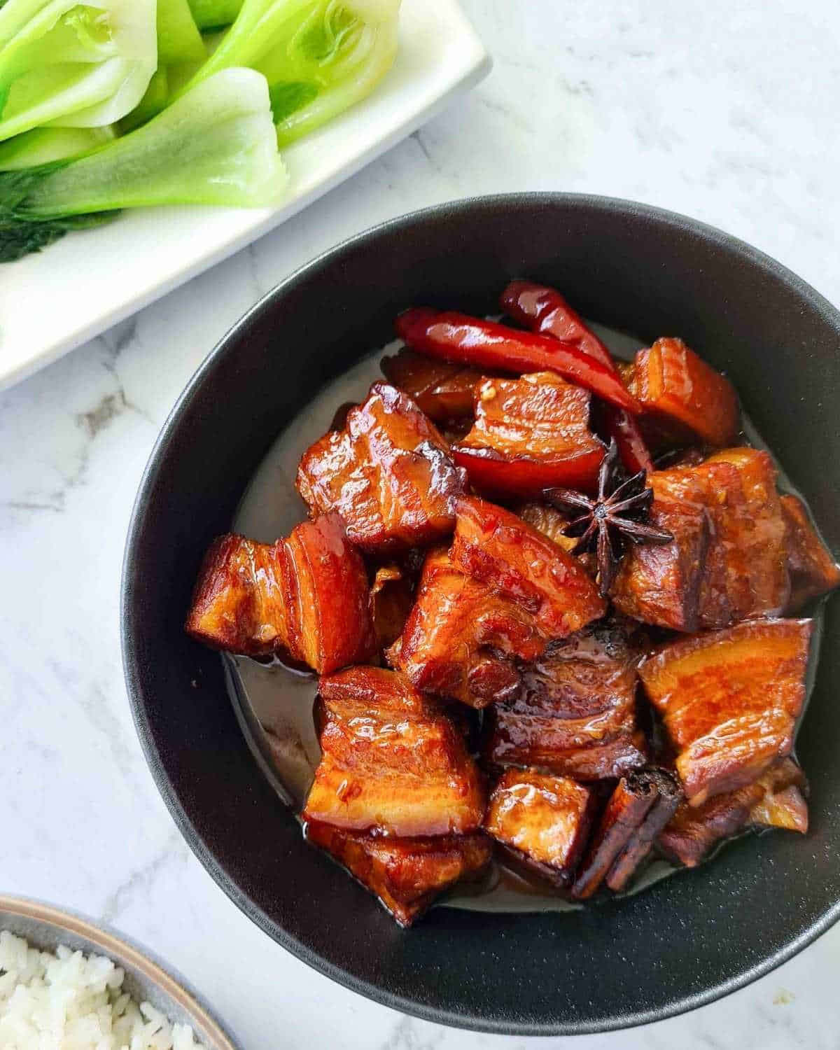 Pork belly with sauce in a large black bowl