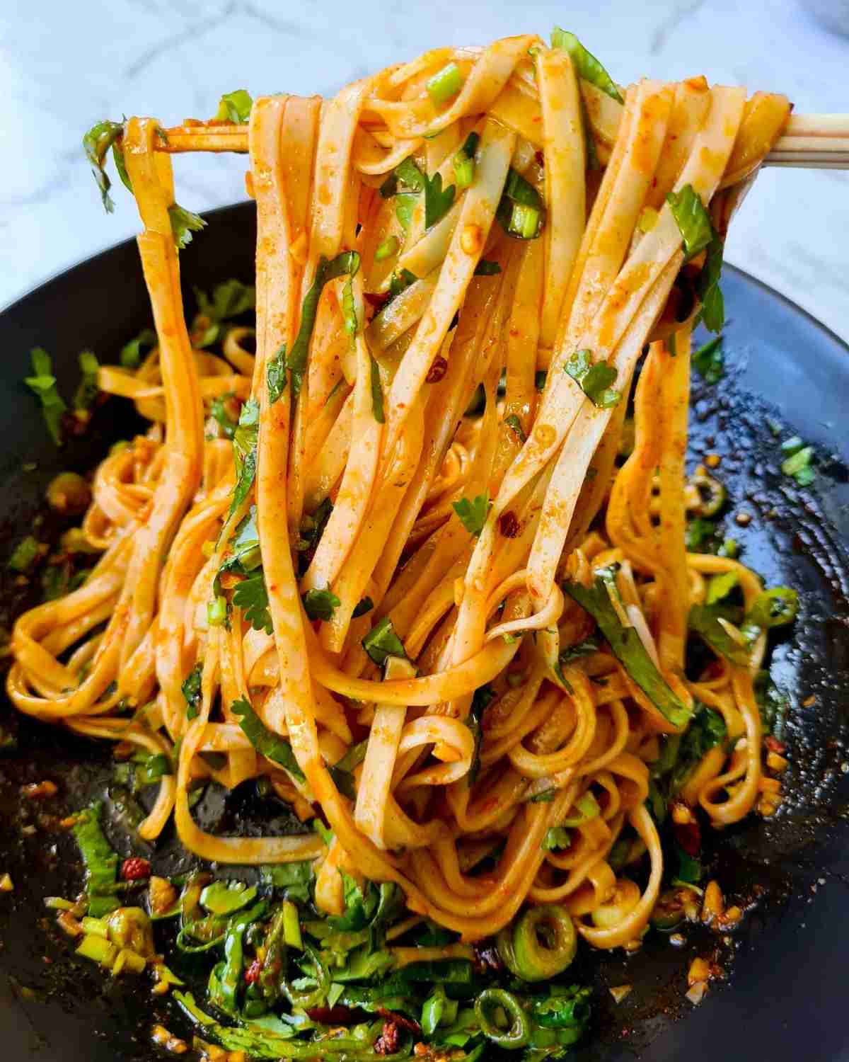 close up of noodles being picked up by a pair of chopsticks