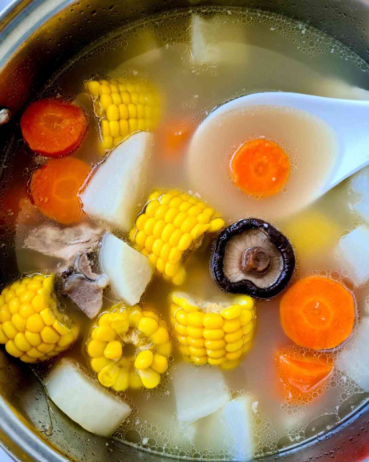 Overhead view of a pot of pork bone soup filled with vegetables 