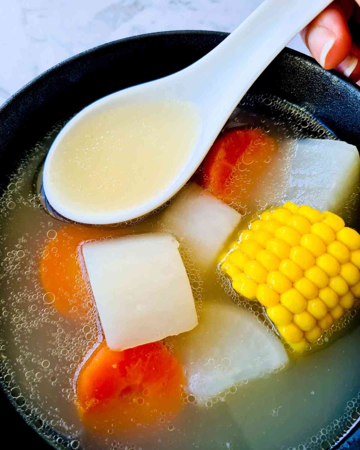 A spoonful of clear soup over a bowl of soup