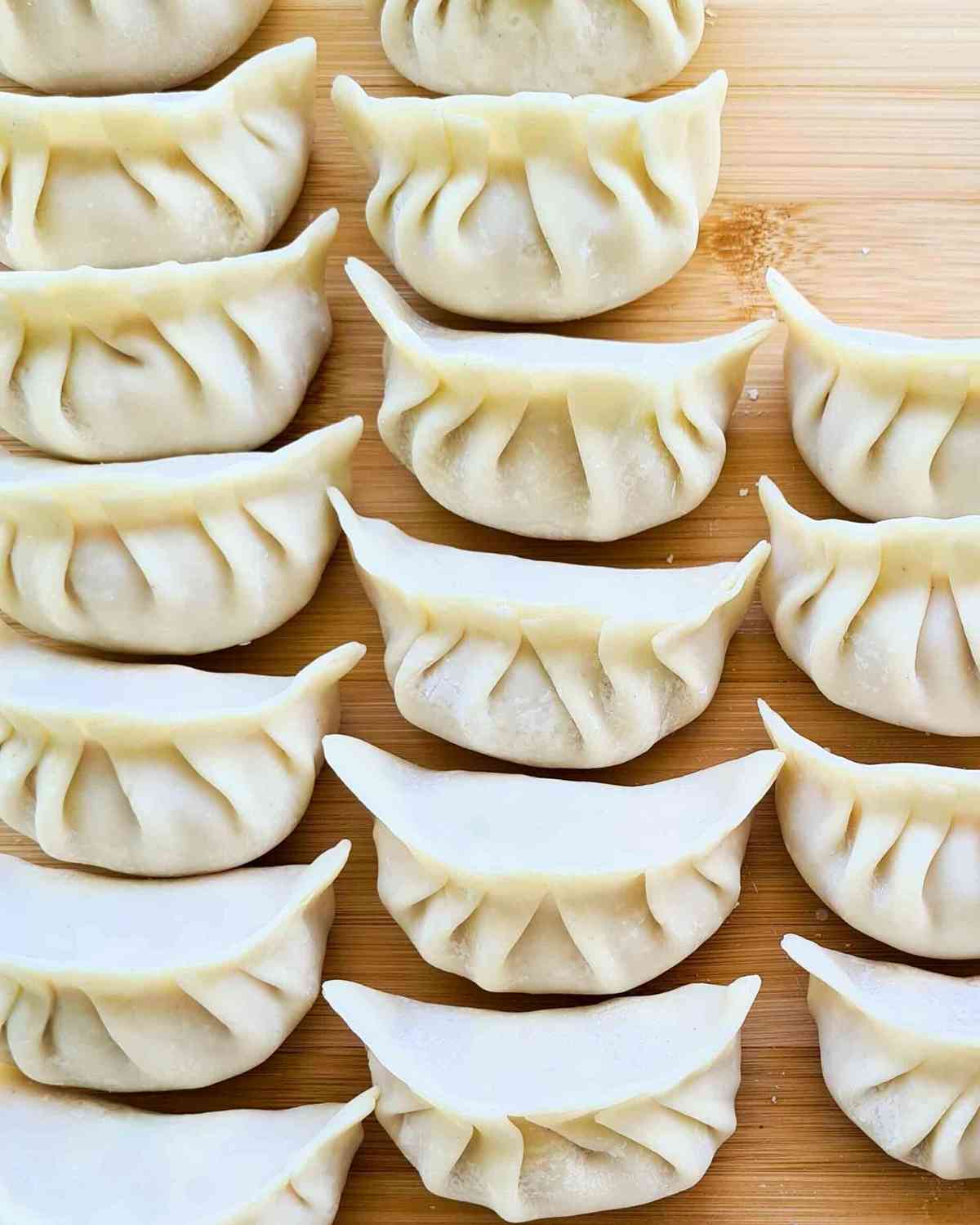 3 rows of neatly pleated dumplings about to be cooked