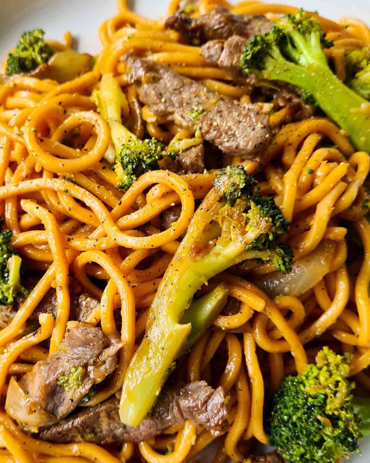 Close up of noodles, broccoli, beef strips and black pepper