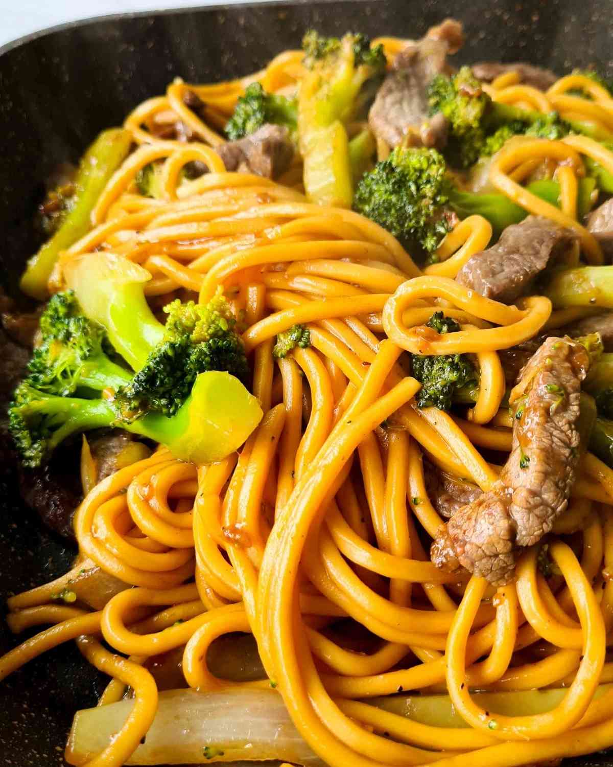 Close up of noodle stir fry steaming from the frying pan