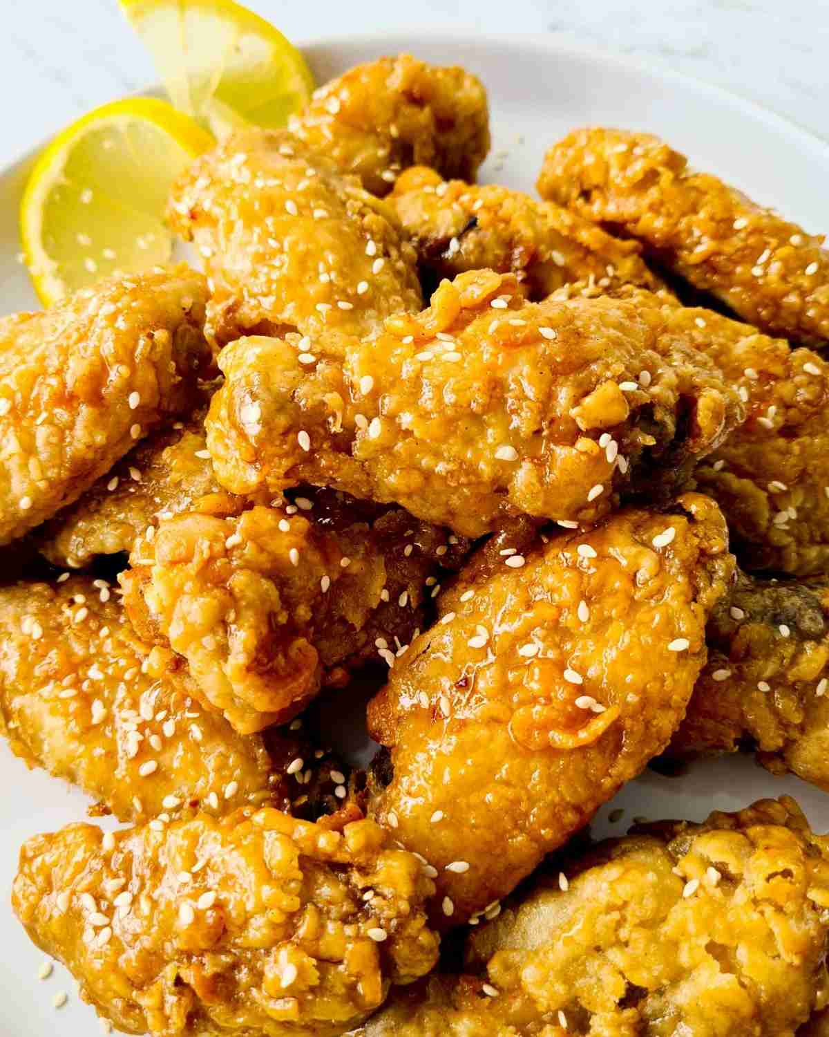 Close up of crispy chicken wings coated with honey sauce and sesame seeds
