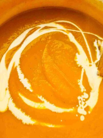 Close up of smooth pumpkin soup drizzled with cream