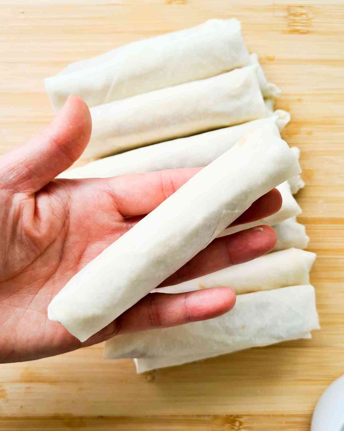 a stack of rolled pastries with one held up by a hand