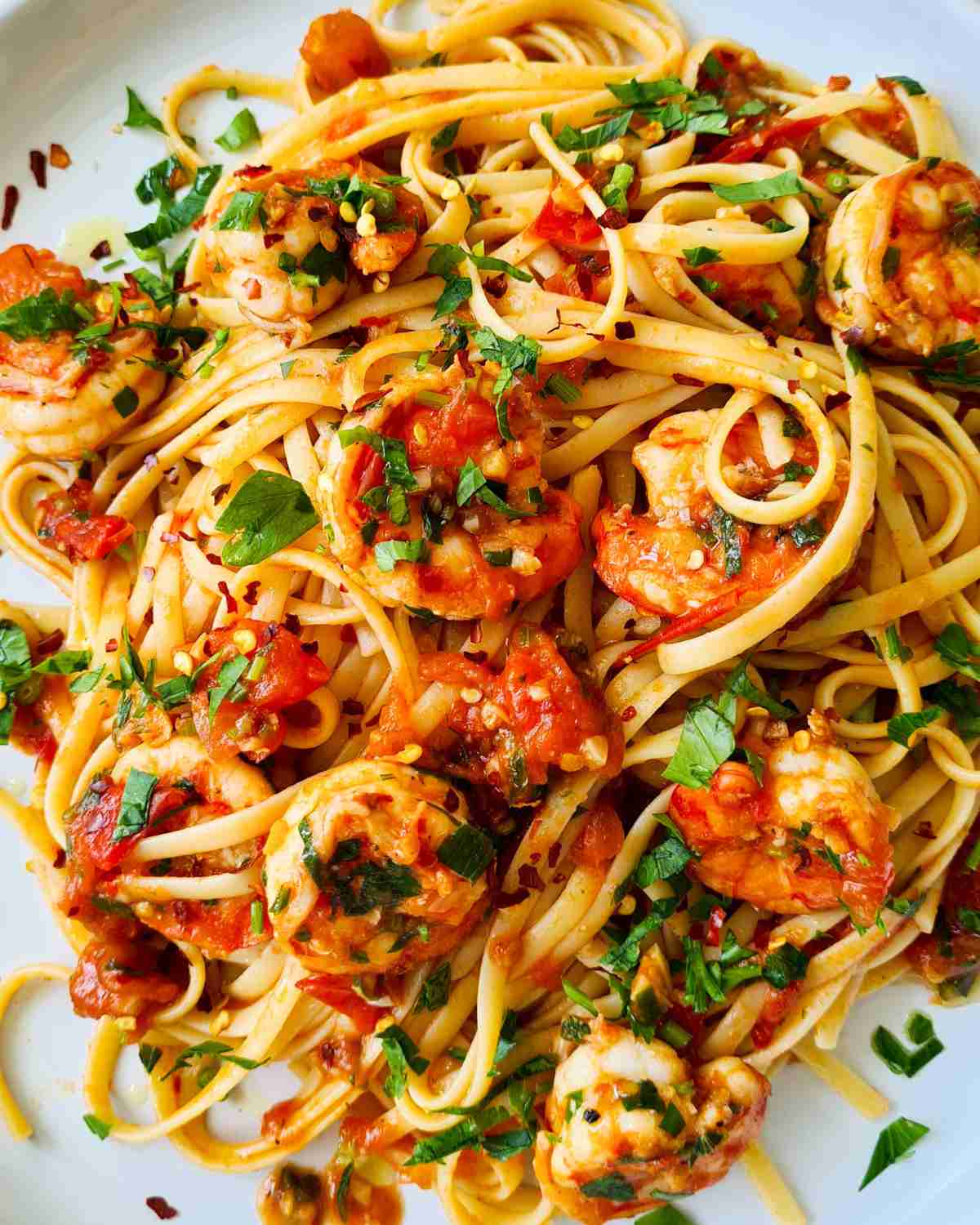 A plate of tomato sauce based prawn pasta sprinkled with chilli flakes