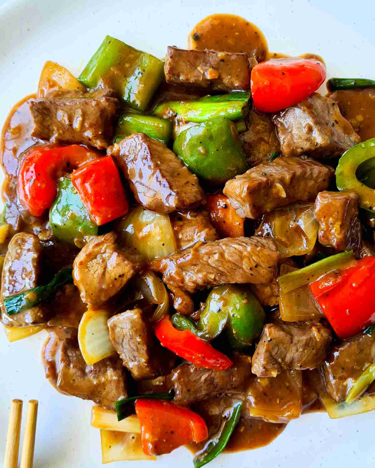 Glossy beef cubes and vegetables on a white plate