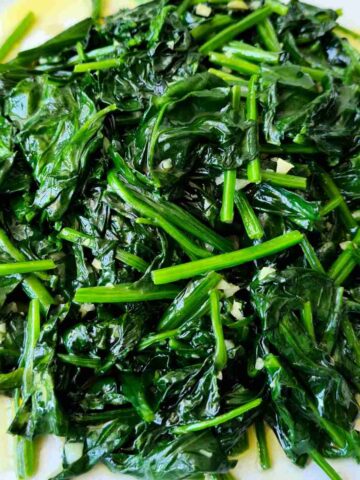 Close up of a plate of glossy stir fried english spinach with garlic