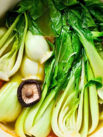 Close up of vibrant bok choy vegetables in soup in a pot