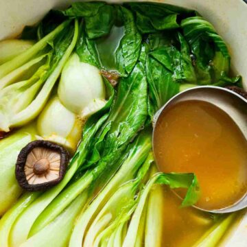 Close up of bok choy soup in a pot with a ladle of soup