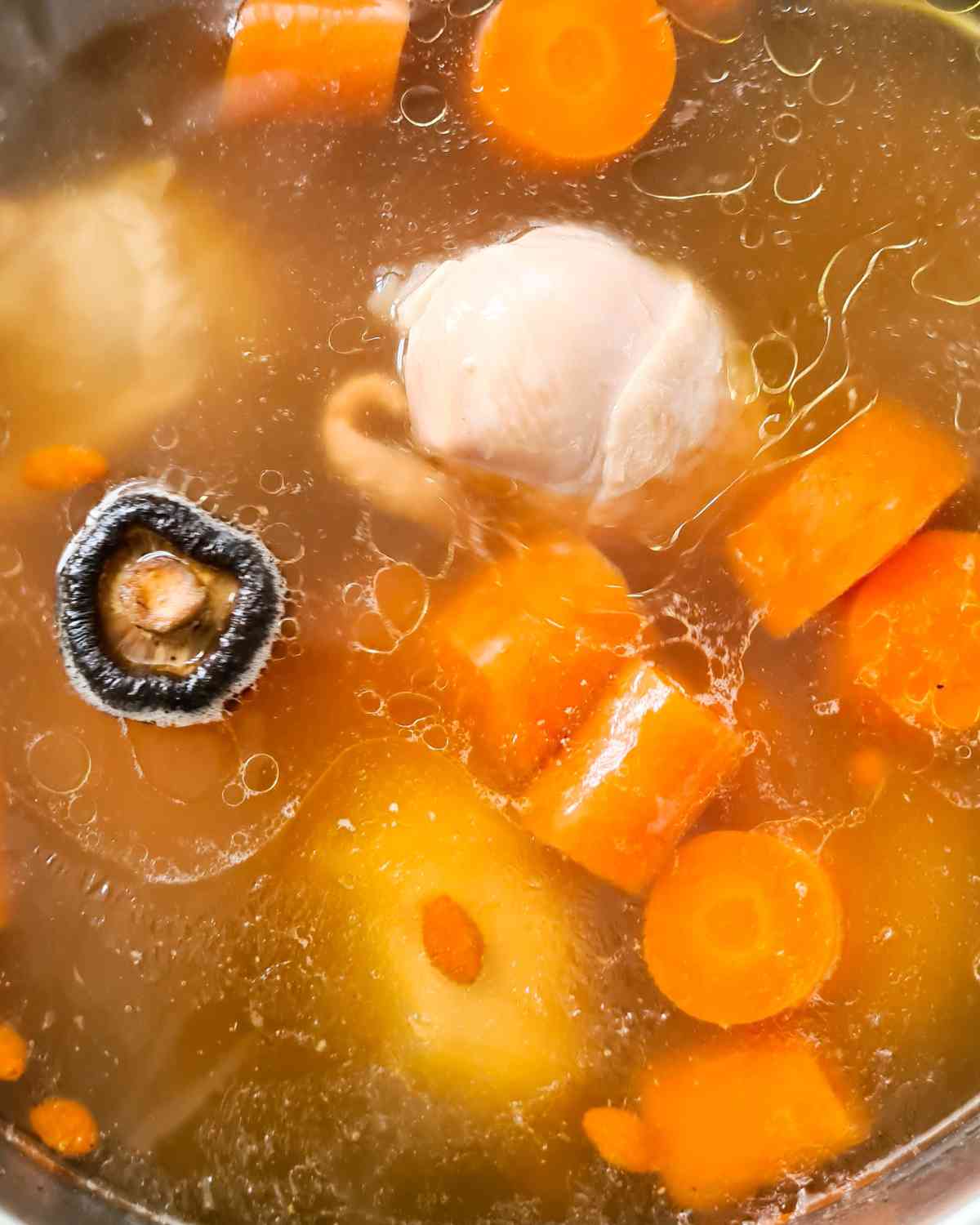 Close up of a pot of clear chicken soup