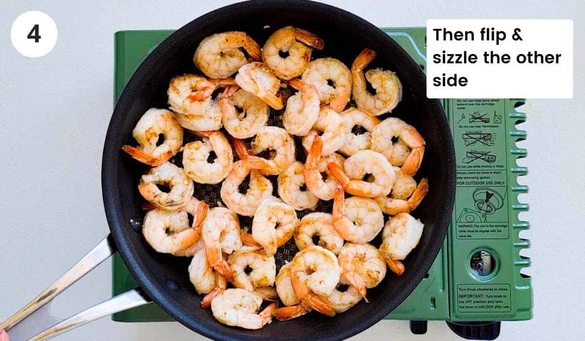 Shrimp (prawns) being sauteed in a frying pan that are cooked with caption